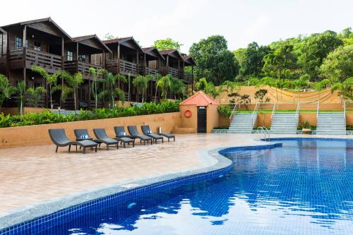 a pool at a resort with chairs around it at Axiom Resorts Luxury Cottages, Arambol in Arambol