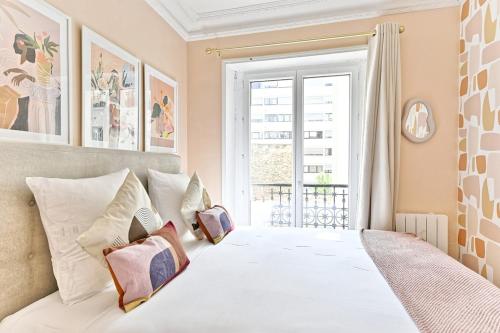 une chambre avec un lit blanc avec des oreillers et une fenêtre dans l'établissement Appartement proche de la Gare Montparnasse-II, à Paris