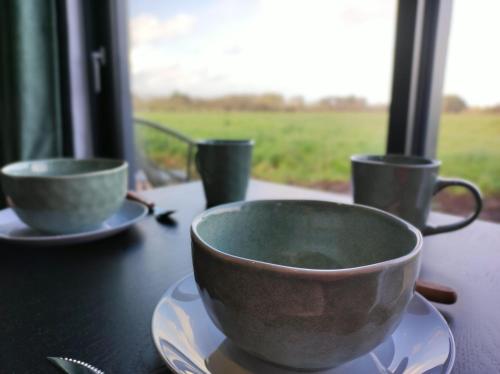 deux tasses et assiettes sur une table avec une fenêtre dans l'établissement La Bulle Bigoudène, à Plobannalec-Lesconil