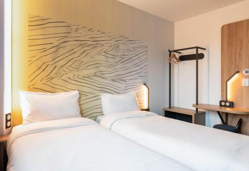 a bedroom with a white bed and a wall at B&B HOTEL Bourg-en-Bresse Viriat in Viriat