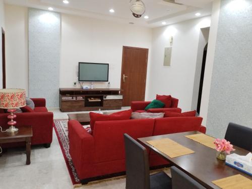 a living room with red couches and a television at بسمة الدهاريز Basmat Aldahariz in Salalah
