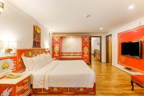 a bedroom with a large bed and a flat screen tv at The Chumbi Mountain Retreat & Spa, A Club Mahindra Associate in Pelling