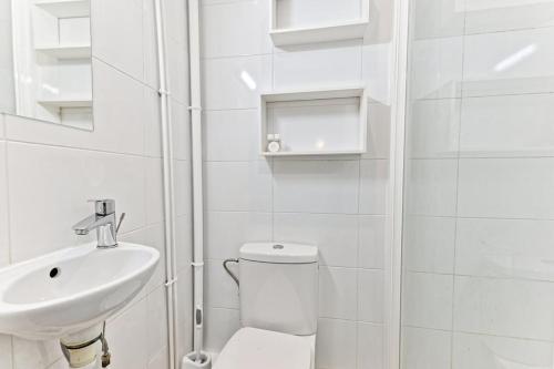 une salle de bain blanche avec des toilettes et un lavabo dans l'établissement Studio cool avec mezzanine 17ème arrondissement, à Paris