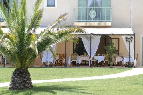 a palm tree in front of a building with tables and chairs at Hotel Restaurant Le Clos De Pradines in Saint-Quentin-la-Poterie