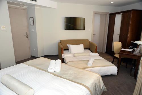 a hotel room with two beds and a desk at Alexandar Square Boutique Hotel in Skopje