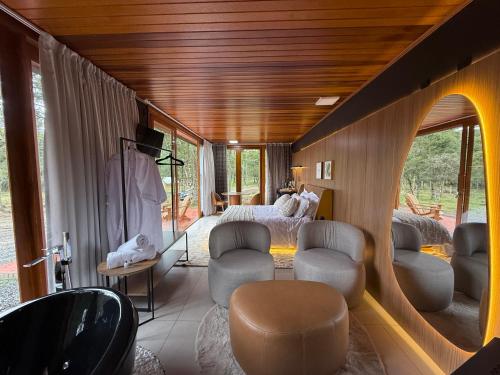 a bedroom with a bed and chairs in a room at Pousada Maçã Araucária in São Joaquim
