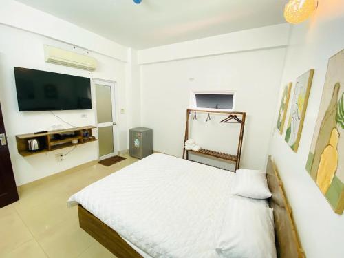a white bedroom with a bed and a flat screen tv at Hi Hotel in Kỳ Vĩ