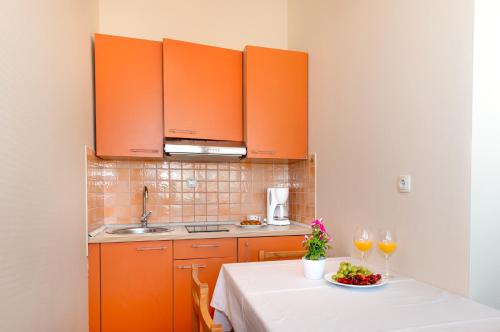 a kitchen with orange cabinets and a table with wine glasses at Villa Lavanda in Primošten
