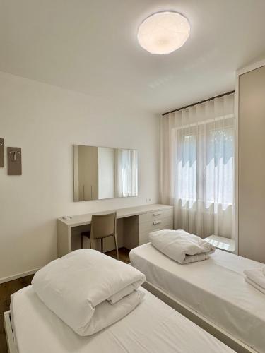 a bedroom with two beds and a desk and a mirror at 1Dest - Le Ginestre Serenity Home in Riva del Garda