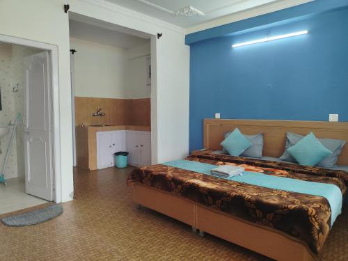 a bedroom with a large bed with a blue wall at Check-in & Chill in Dharamshala