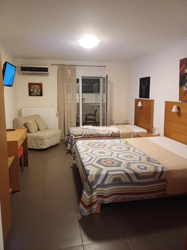 a hotel room with three beds and a television at Crystal Aura in Paralia Katerinis