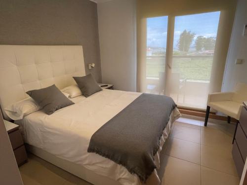 sypialnia z białym łóżkiem i dużym oknem w obiekcie Apartamentos Lanceata I w mieście A Lanzada