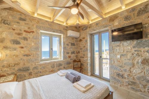 a bedroom with a bed and a tv on a stone wall at Villa Dioni Thio in Pírgos