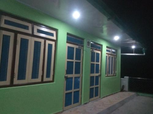 a room with green walls and doors at night at Ma Kokila Homestay in Munsyari