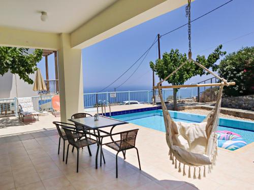 a patio with a table and chairs and a hammock at Villa Lawton - Magnificent sea & mountain views! in Epáno Kefalás