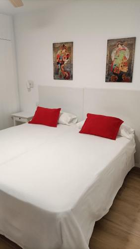 a large white bed with two red pillows on it at Apartamento ValentinaBeach in Torrox Costa