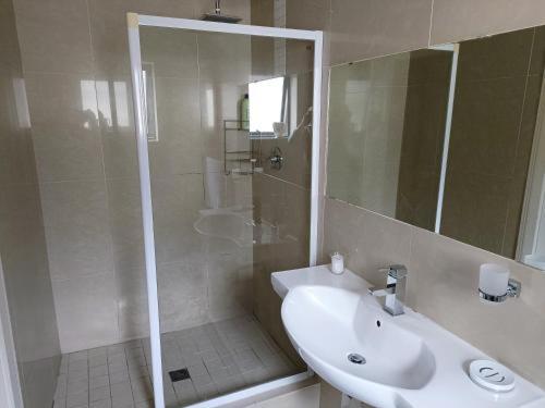 a white bathroom with a sink and a shower at Camdene Guesthouse in Cape Town