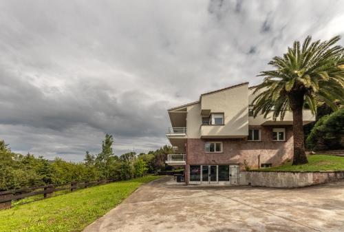 a house with a palm tree in front of it at Aston - Villa Islas Urdaibai in Isla Becoa