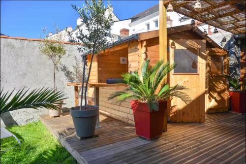 una terraza de madera con dos macetas. en Velours 4 & Jacuzzi, en Saint-Nazaire