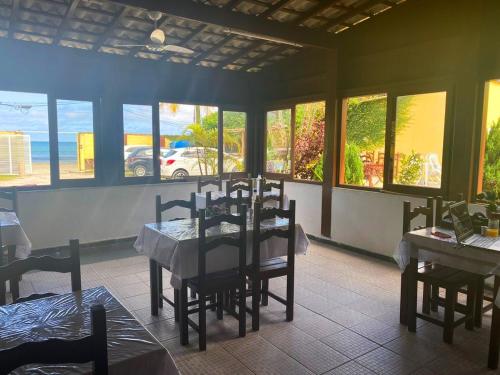 a dining room with a table and chairs and windows at Piscina e Mar PousadaH in Guarujá