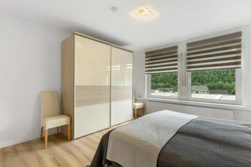 a bedroom with a bed and two windows at Schwalbennest in Lennestadt