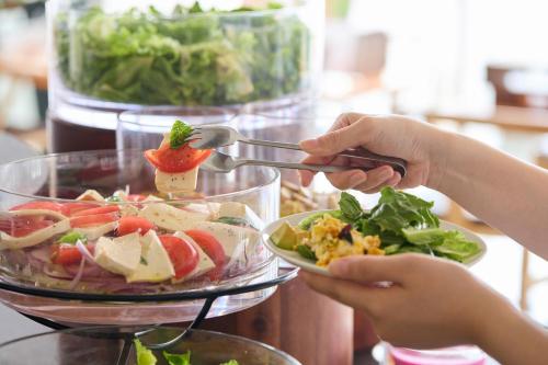 a person is serving a salad in a bowl at Naha Tokyu REI Hotel in Naha