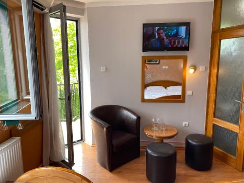 a living room with a chair and a tv on a wall at Vila Madams - Palić-Serbia in Palić