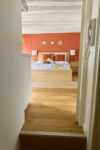 une chambre avec un lit avec un mur orange dans l'établissement PETIT HORLOGE, à Rouen