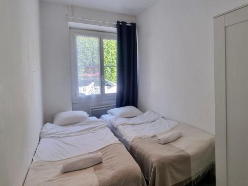 deux lits dans une chambre avec une fenêtre dans l'établissement Monaco CARNIER Parking, à Beausoleil