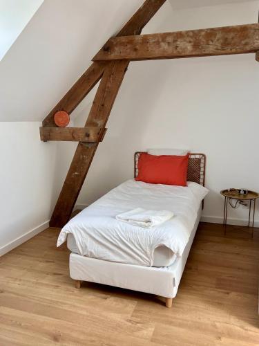 une chambre avec un lit blanc avec un oreiller rouge dans l'établissement Maison Origines - Escapade au vert, à Heudicourt