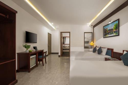 a hotel room with a bed and a desk at An Hotel in Hoi An