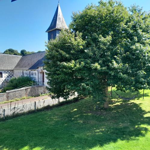 un arbre dans l'herbe devant une église dans l'établissement Le Grenier, à Saint-Christophe-sur-Condé