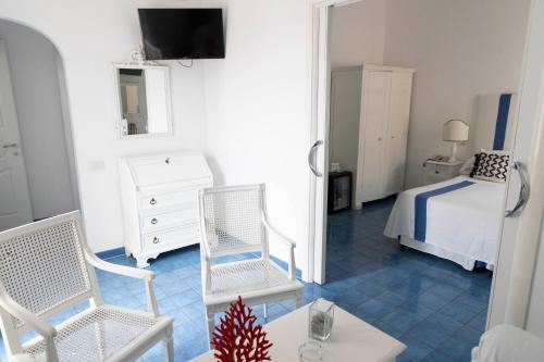 a room with a bed and two chairs and a table at Hotel Chiaia Di Luna in Ponza