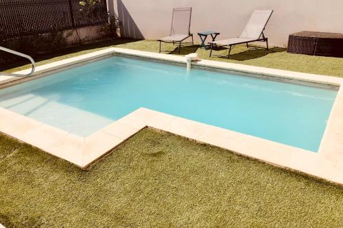 - une piscine avec deux chaises dans la cour dans l'établissement Pleasant modern house t4 airco pool parking, à Juvignac