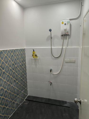 a bathroom with a shower with a hose on the wall at Cat in the box homestay in Godown