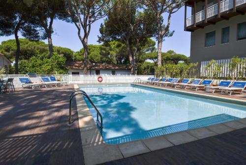 a swimming pool with lounge chairs and a building at Hotel Columbia in Marina Romea