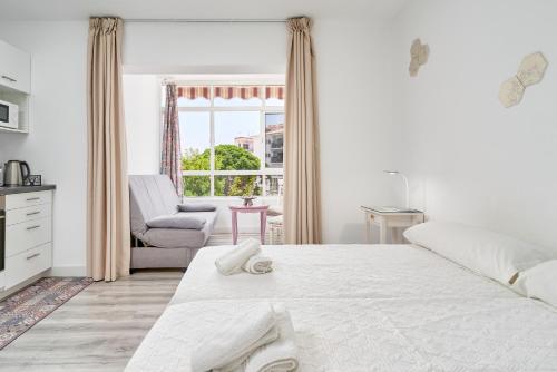 une chambre blanche avec un lit et une chaise dans l'établissement Loft La Marina in Nerja, à Nerja