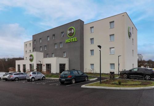 a hotel with cars parked in a parking lot at B&B HOTEL Le Creusot Montchanin in Montchanin