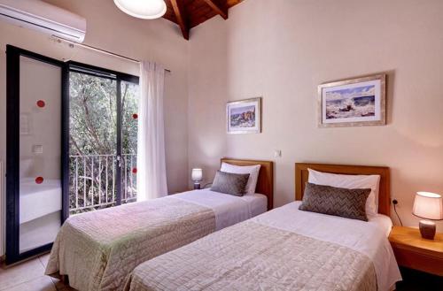 two beds in a room with a window at Villa Ithaki Kefalonia in Lourdhata