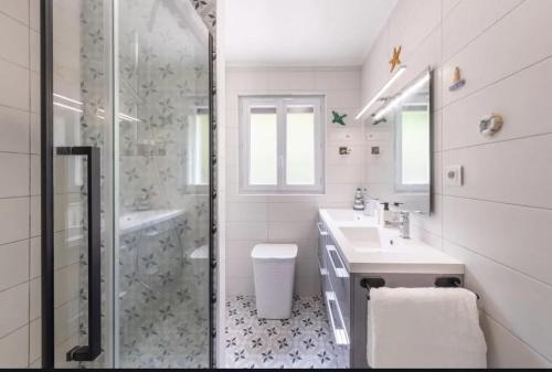 une salle de bain blanche avec une douche et un lavabo dans l'établissement Maison confortable avec jardin à Le Tréport, au Tréport