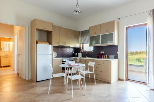 a kitchen with a table and chairs and a refrigerator at Stella by Hospi in Kato Gouves