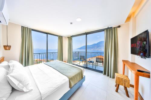 a bedroom with a bed and a desk and large windows at Lyxos Hotel in Kas