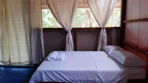 a bedroom with a bed and two windows at Iracas del Mar in Termales - agua caliente - nuqui