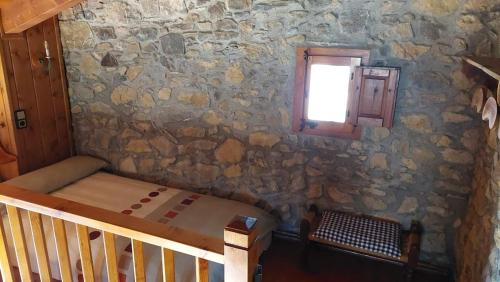 a bedroom with a stone wall with a bed and a window at La caseta de Mas Salelles 