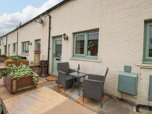 a patio with chairs and a table in front of a building at Yeat Stoup Cottage in Cockermouth