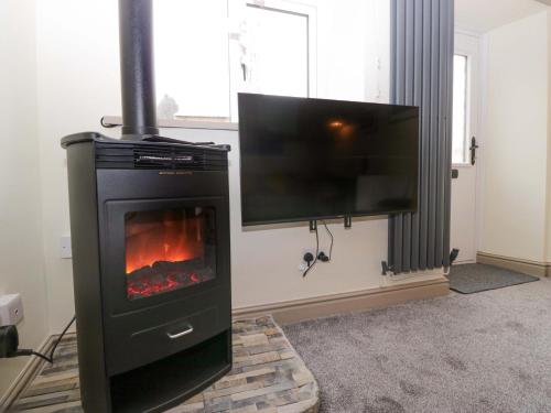 a living room with a fireplace with a flat screen tv at Yeat Stoup Cottage in Cockermouth