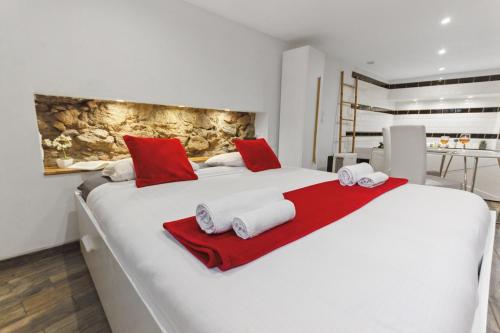 a white bed with red pillows and towels on it at La Suite Confidentielle - Balneo - Sauna - Hypercentre in Cannes