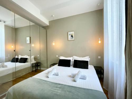 une chambre avec deux lits et un grand miroir dans l'établissement PARISIAN HOME l BELLAN, à Paris