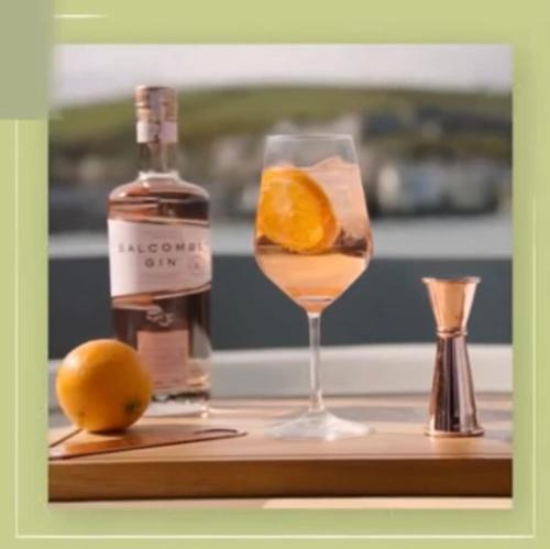 a bottle of alcohol and a glass with an orange at Boat-Hôtel VCB Namur Centre-ville in Namur