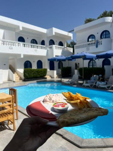eine Person mit einem Teller Essen neben einem Pool in der Unterkunft Sea Horse Hotel Dahab in Dahab